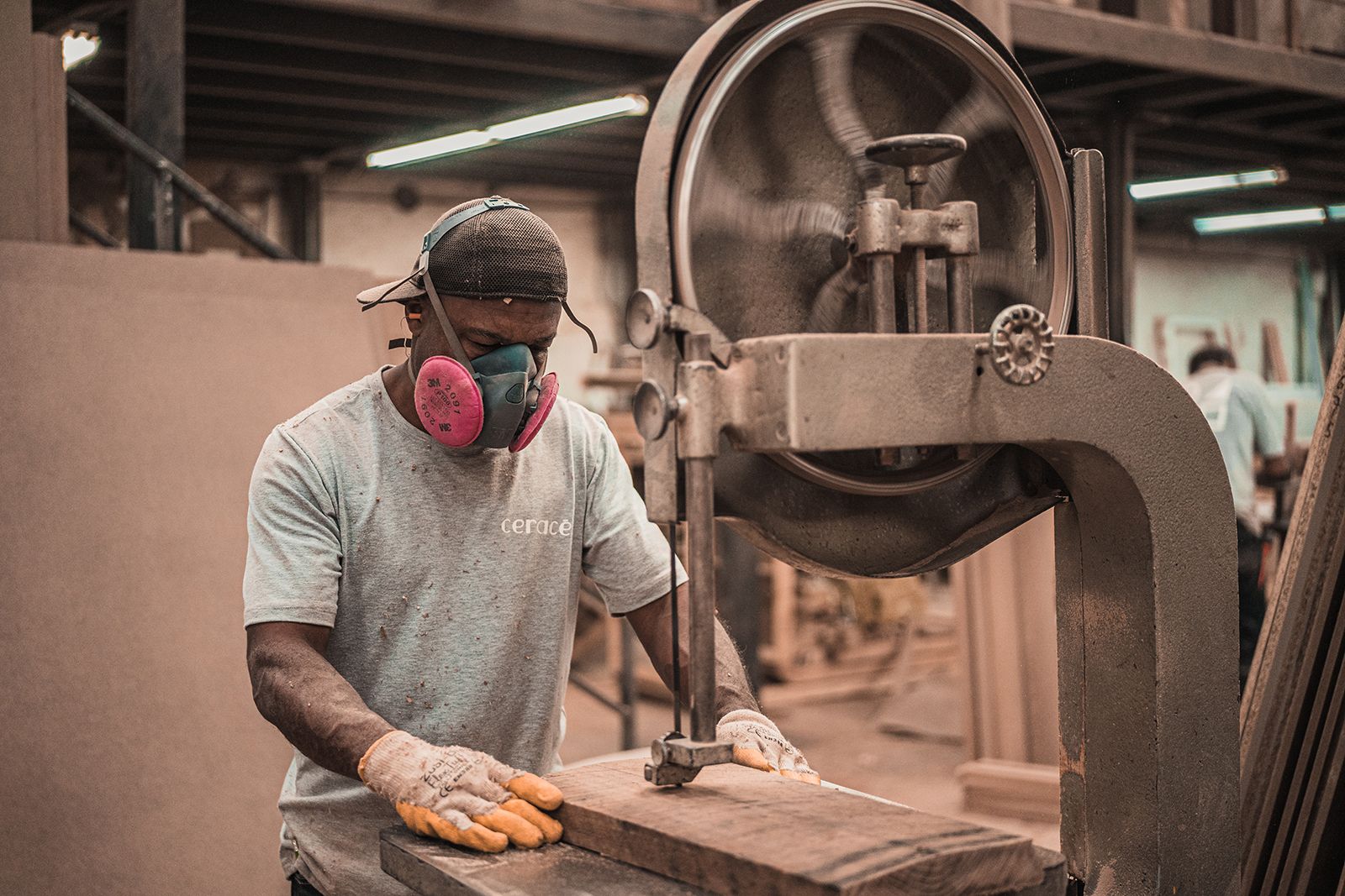 Worker using band saw to cut wood in a heavily dusty environment