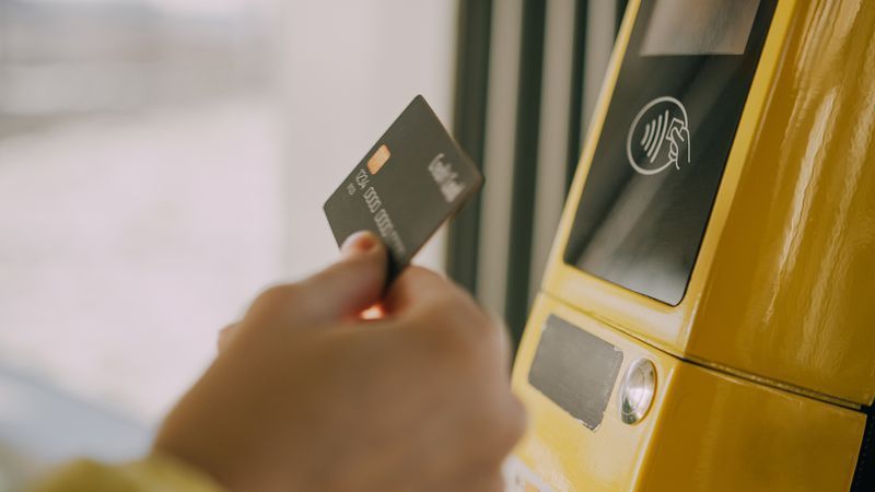 A man making a contactless payment for the bus by tapping his transportation card on an RFID reader