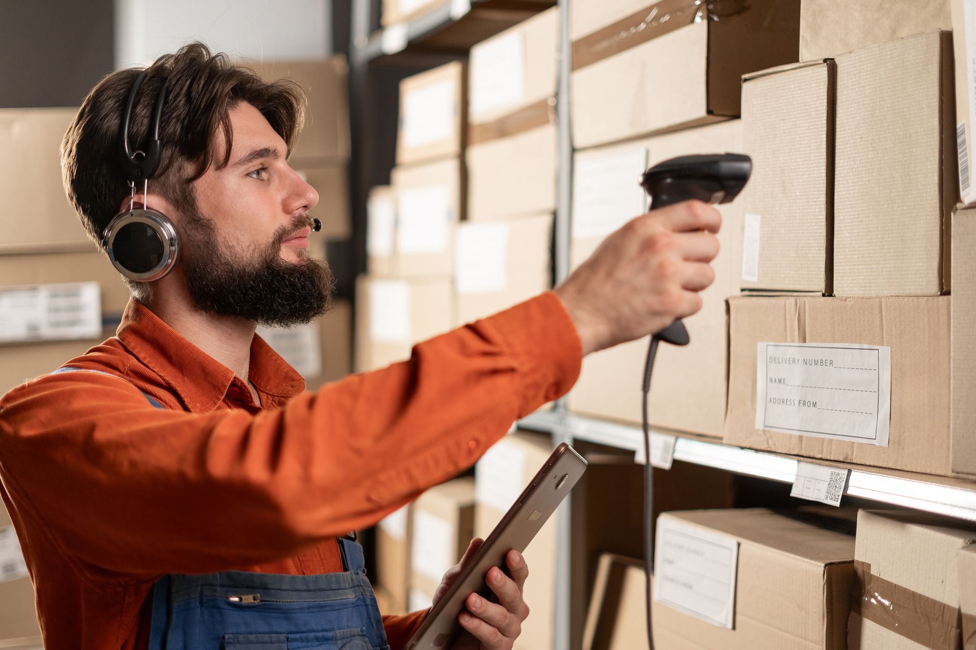 A warehouseman pointing a barcode scanner at a box.