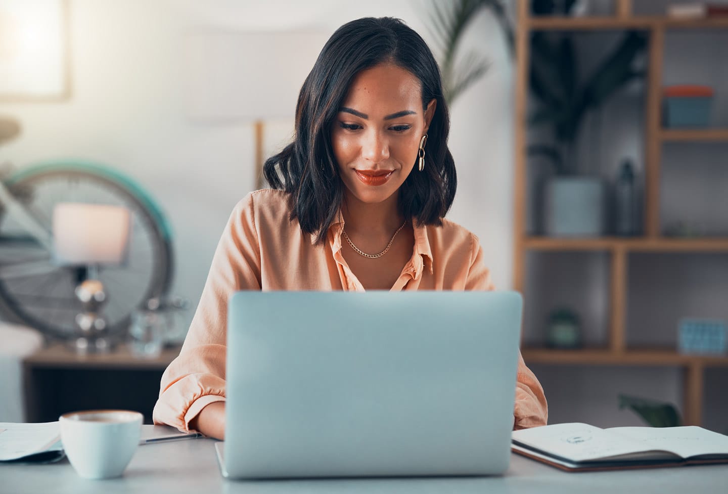 A woman typing on a silver laptop.