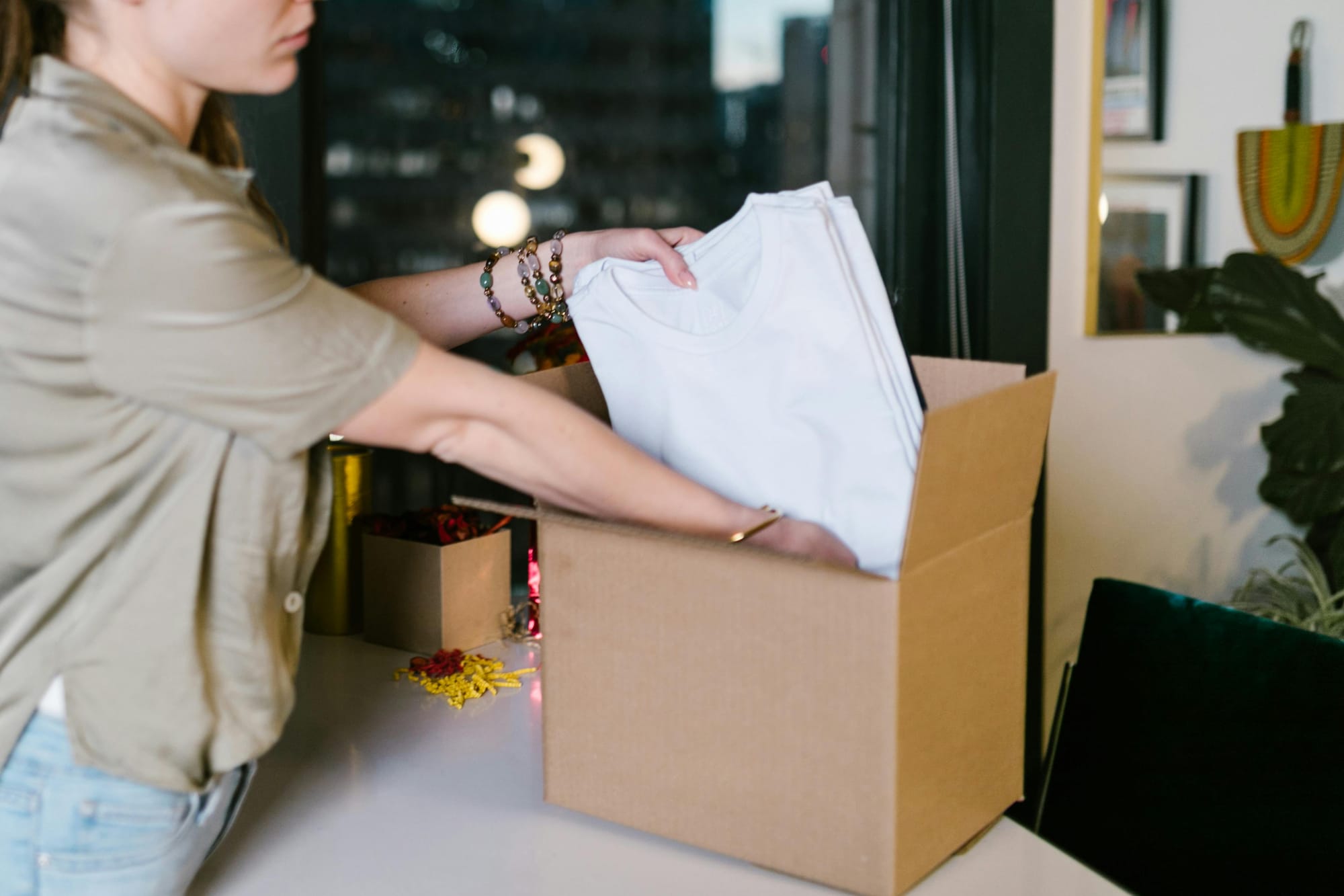 Small business owner packing clothing products into a box for shipping.