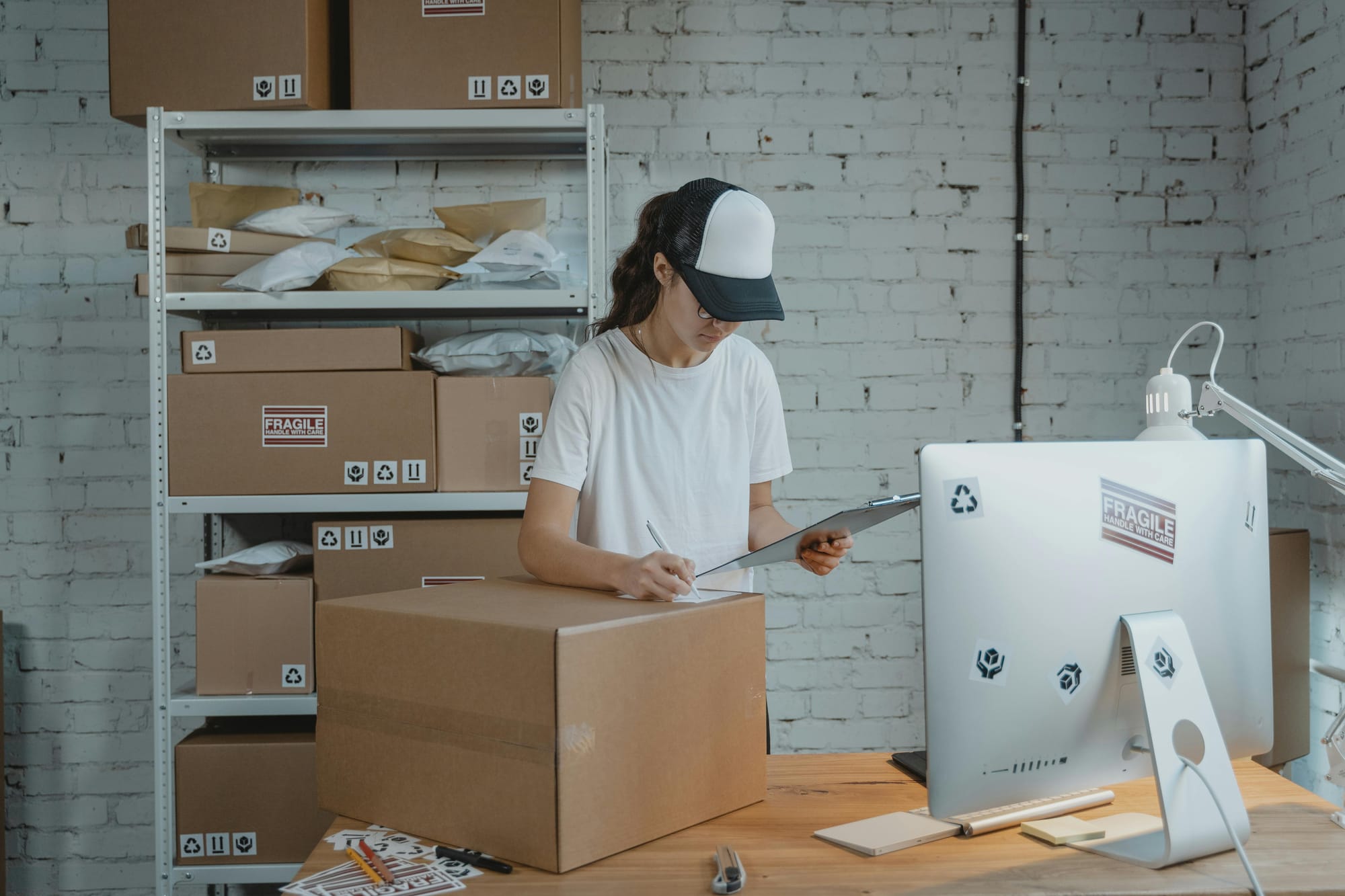 A small business owner tracking orders and packages with a clipboard.