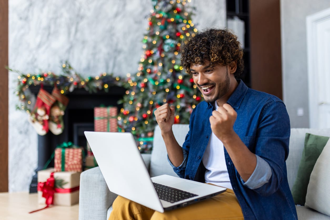 Happy man working with laptop on sofa in living room for christmas and new year holiday