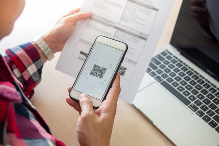 A person using a mobile phone to scan the QR code on a document