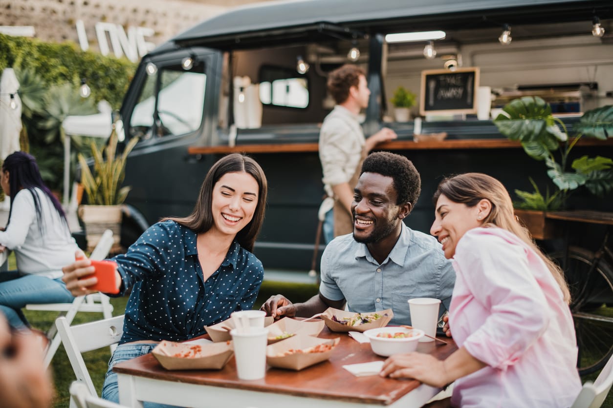 A group of friends enjoying their meal in front of a food truck