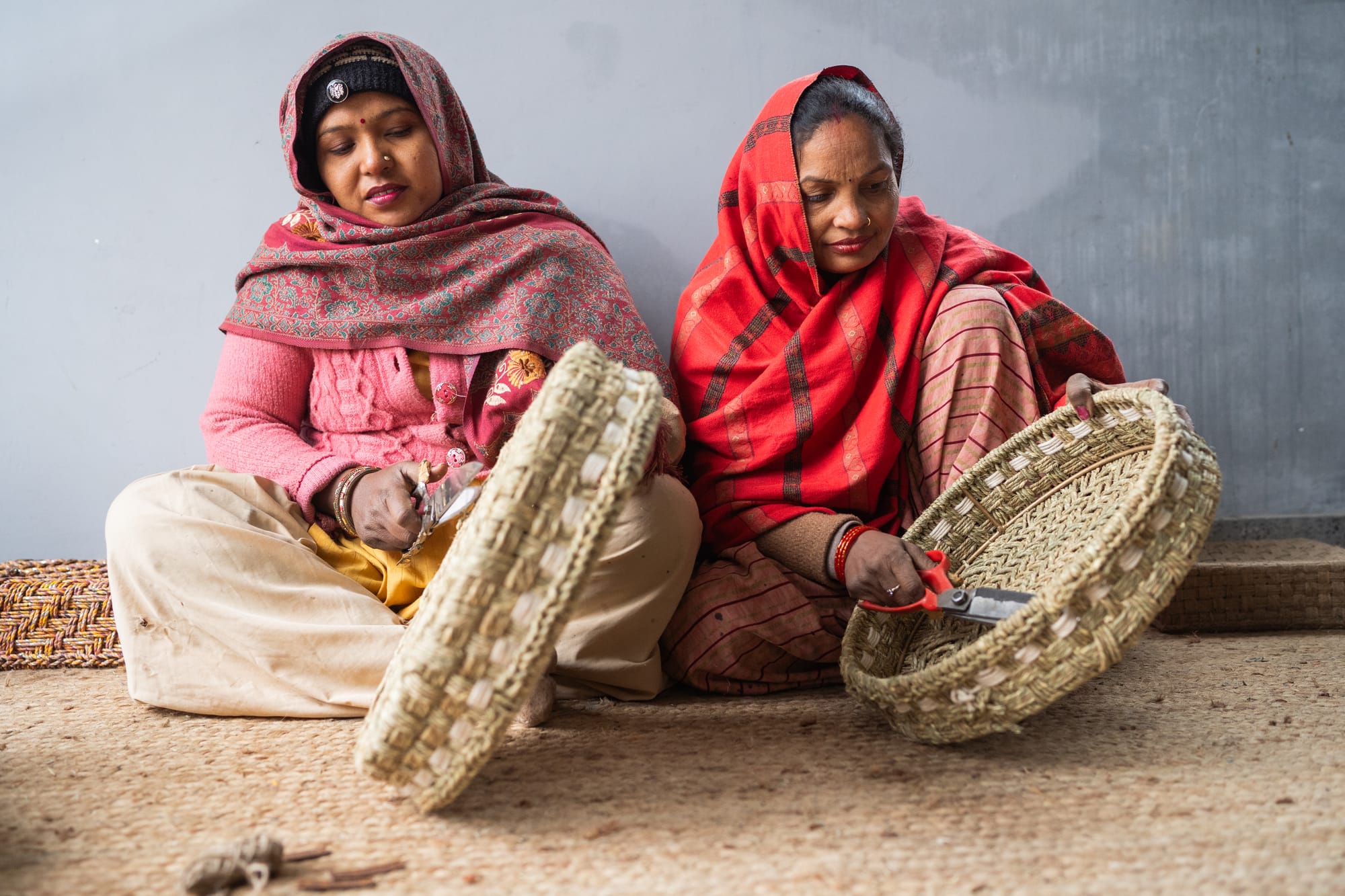 Two women artisans skillfully weaving trays 