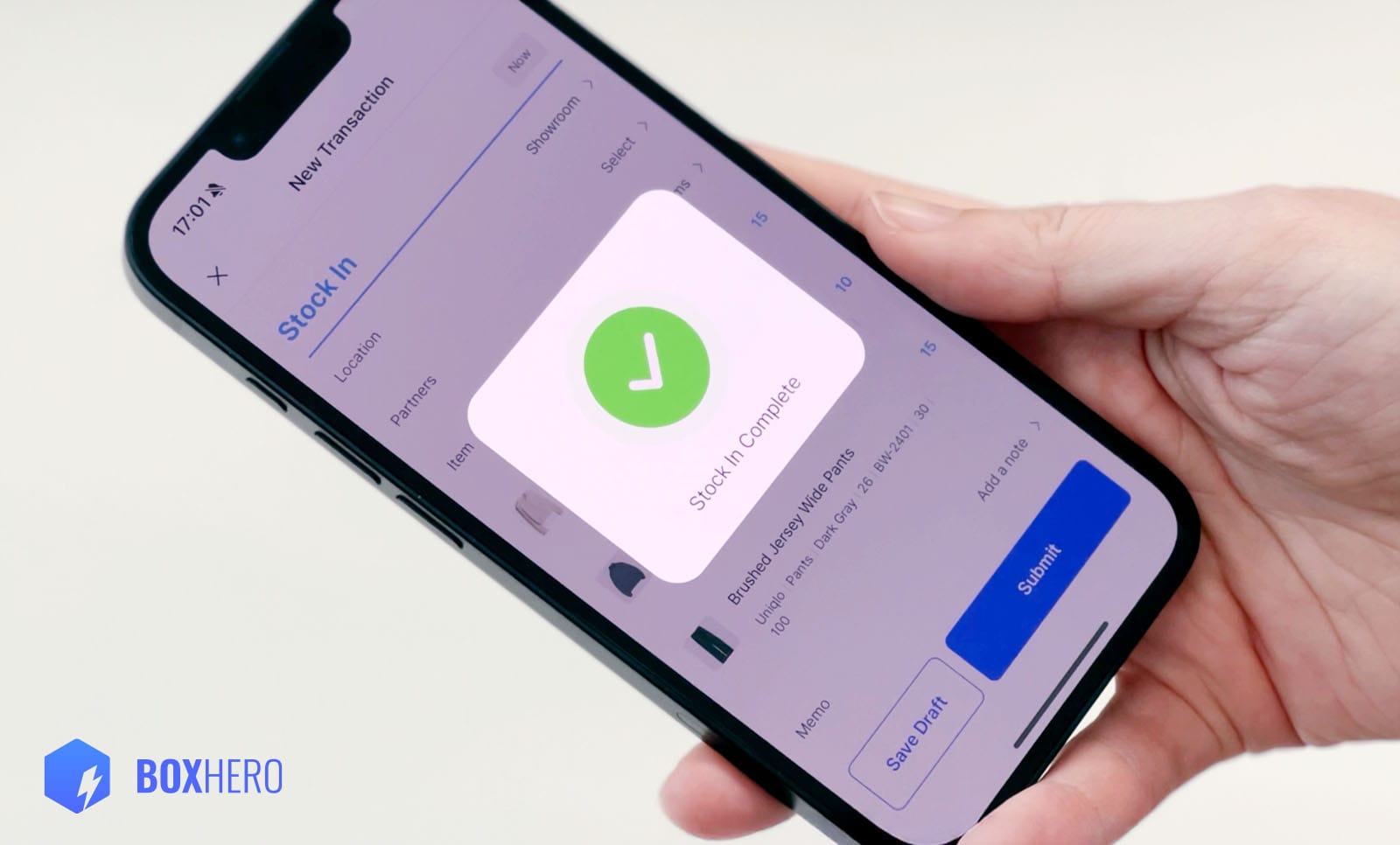 Person holding a smartphone showing the BoxHero app with a ‘Stock In Complete’ confirmation screen.
