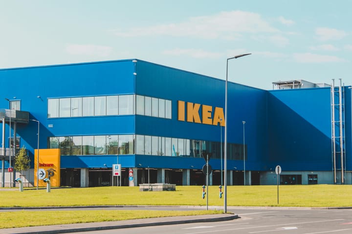 Large blue IKEA store exterior with bold yellow logo on a sunny day.