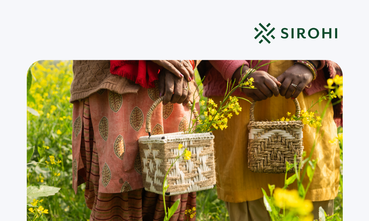 Two women artisans holding intricately woven baskets they handcrafted